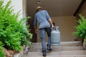 Homem a transportar botija de gás. Crédito: Freepik