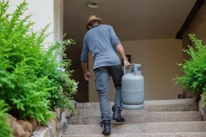 Homem a transportar botija de gás. Crédito: Freepik