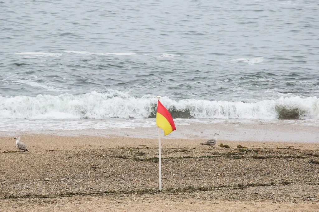 Bandeira com riscas amarela e vermelha na praia.
