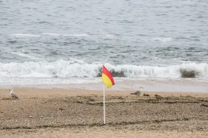 Bandeira com riscas amarela e vermelha na praia.