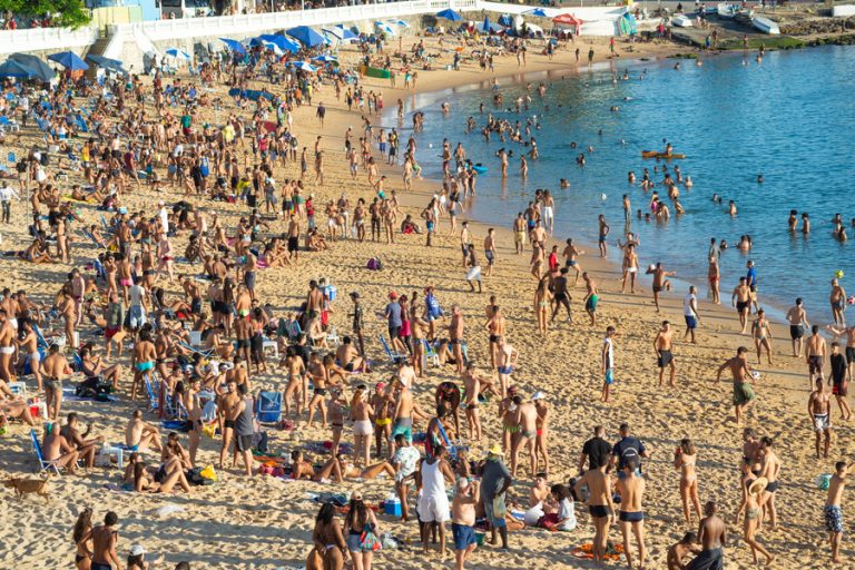 Praia cheia de turistas. Crédito: Freepik