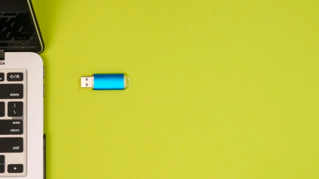 USB paměť u notebooku na žlutém podkladu