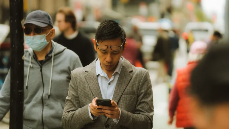 Muž používá mobilní telefon na městské ulici